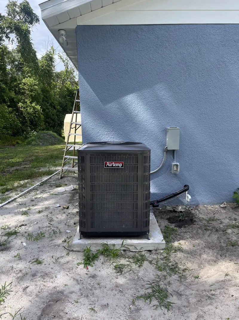 New Airtemp condenser installed on a concrete pad beside a blue stucco home in Central Florida