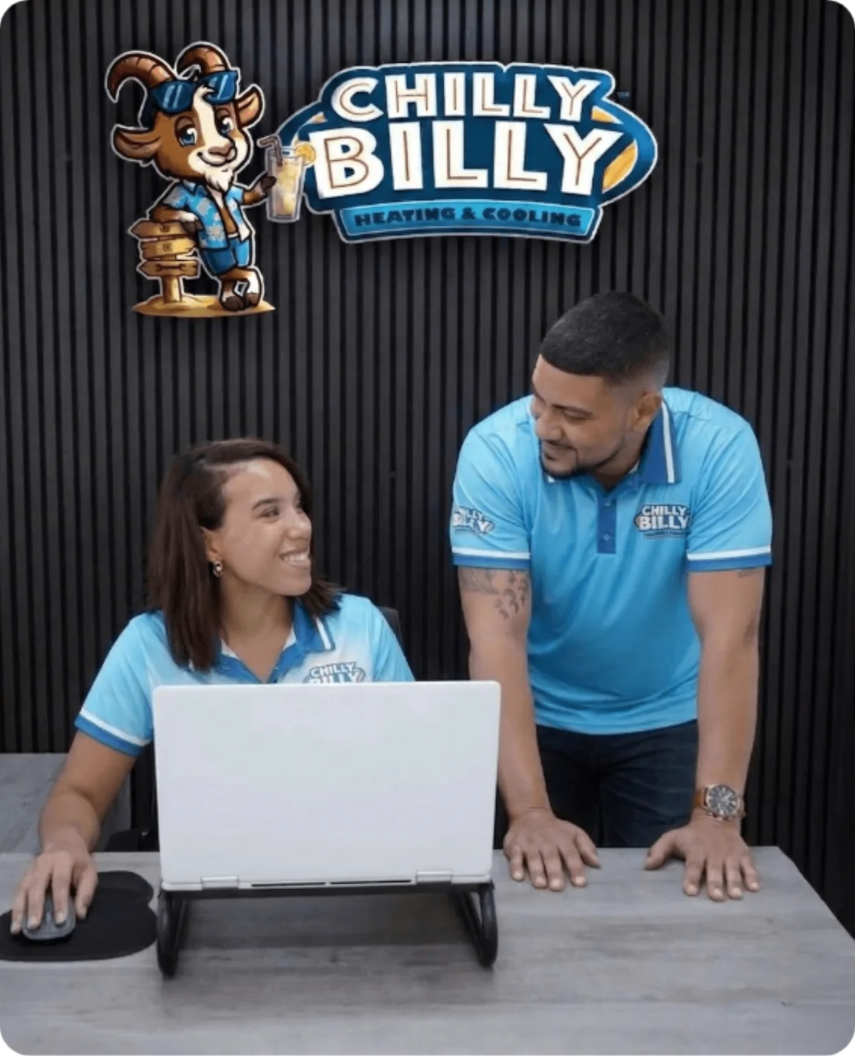 Two Chilly Billy team members in company polos reviewing plans on a laptop at the office