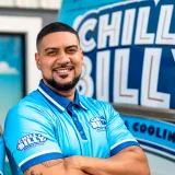 Chris Javier, owner and license holder of Chilly Billy Heating & Cooling, in a company polo in front of the wrapped service van