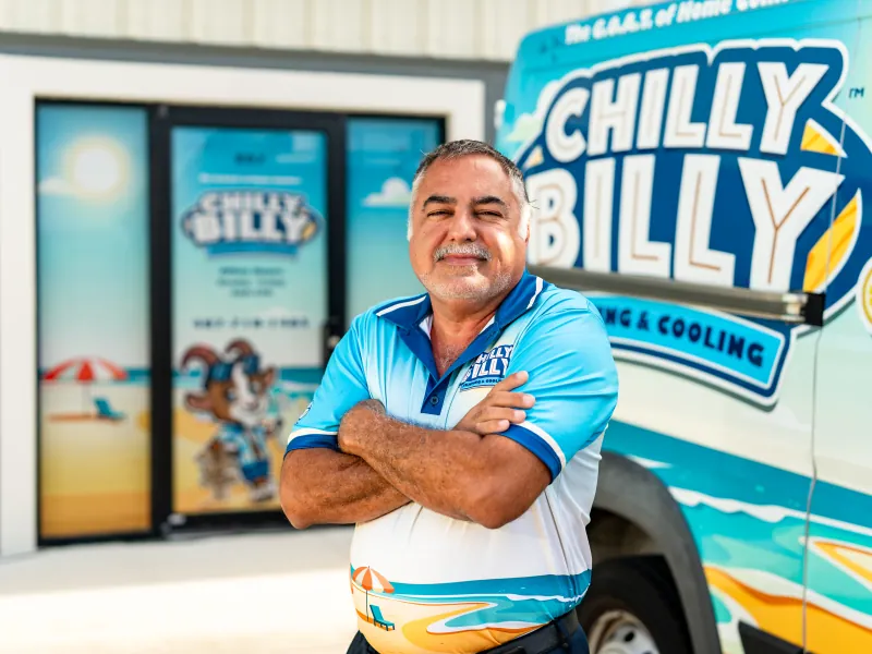 Chris Mendez, project manager at Chilly Billy Heating & Cooling, arms crossed in front of the company van