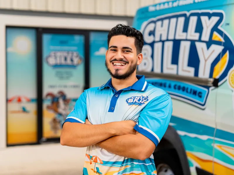 Juan, lead service technician at Chilly Billy Heating & Cooling, smiling in a company polo by the service van