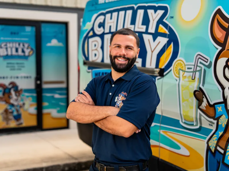 Victor, lead install technician at Chilly Billy Heating & Cooling, in a navy company polo in front of the van wrap